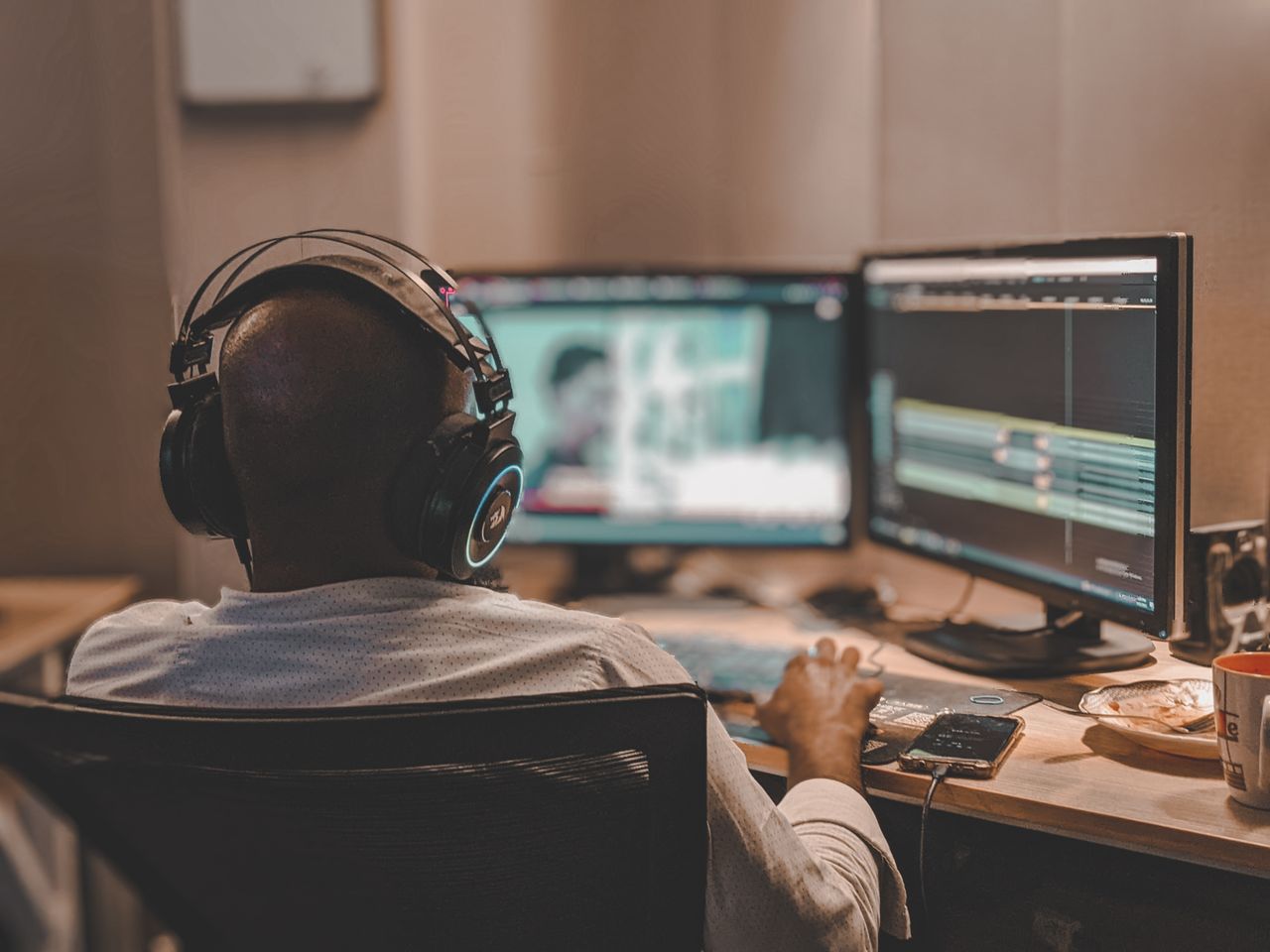 Crafting Captivating Headlines: Your awesome post title goes here Back view of a man with headphones working on video editing in Lahore office.