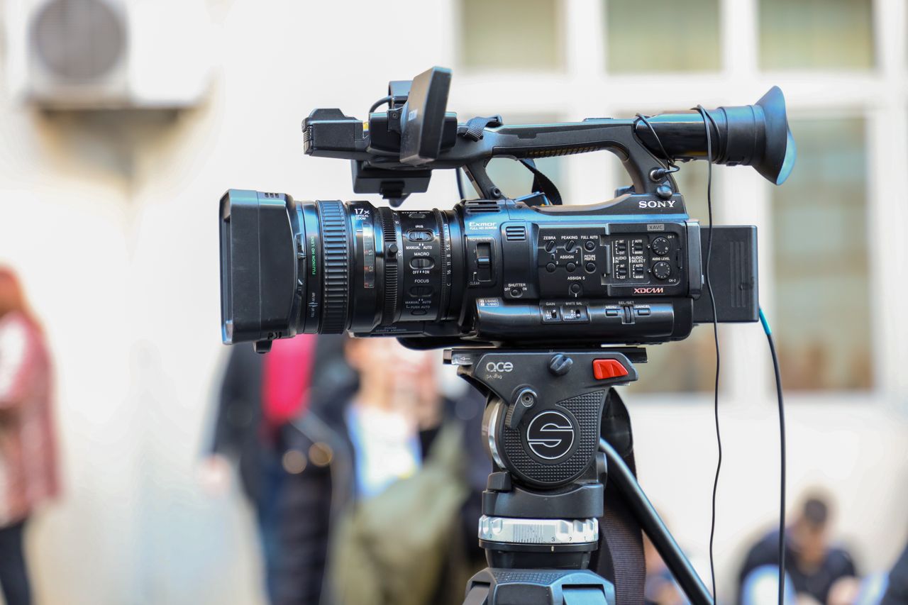 portfolio-07 Close-up of a Sony video camera mounted on a tripod for outdoor filming.