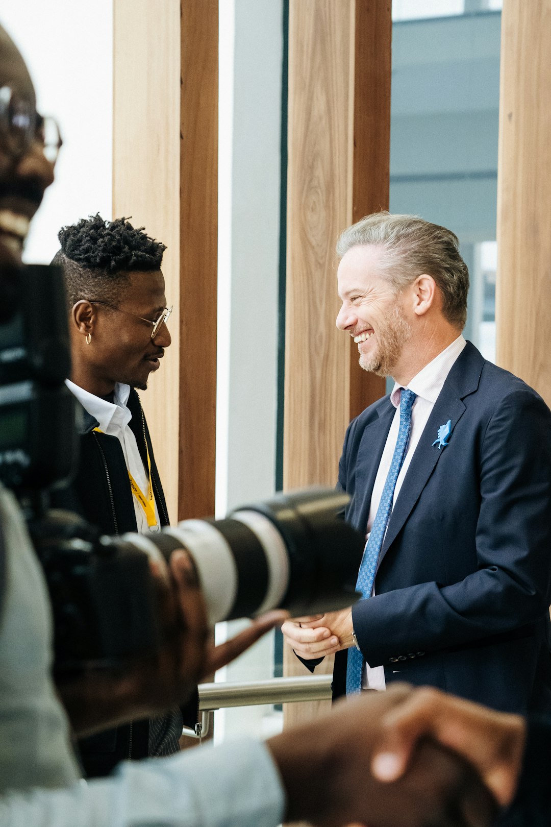 portfolio-04 two-men-greet-each-other-while-being-photographed-dlusl7-xoww